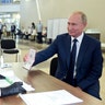 Russian President Vladimir Putin shows his passport to a member of an election commission as he arrives to take part in voting at a polling station in Moscow, Russia, July 1, 2020. 