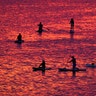 People steer their paddleboards at sunset on the Velikaya River in Pskov, Russia, July 6, 2020. 