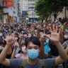 Protesters against the new national security law gesture with five fingers, signifying the "Five demands - not one less" on the anniversary of Hong Kong's handover to China from Britain in Hong Kong, July. 1, 2020. 