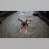 A Nepalese man jumps into the Bagmati river during monsoon rains in Kathmandu, July 20, 2020.