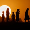 Children are silhouetted against the sunset while playing on a hilltop on the outskirts of Islamabad, Pakistan, July 5, 2020.