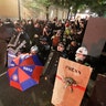 Demonstrators shield themselves from advancing federal officers during a Black Lives Matter protest Tuesday, July 28, 2020, in Portland, Ore.