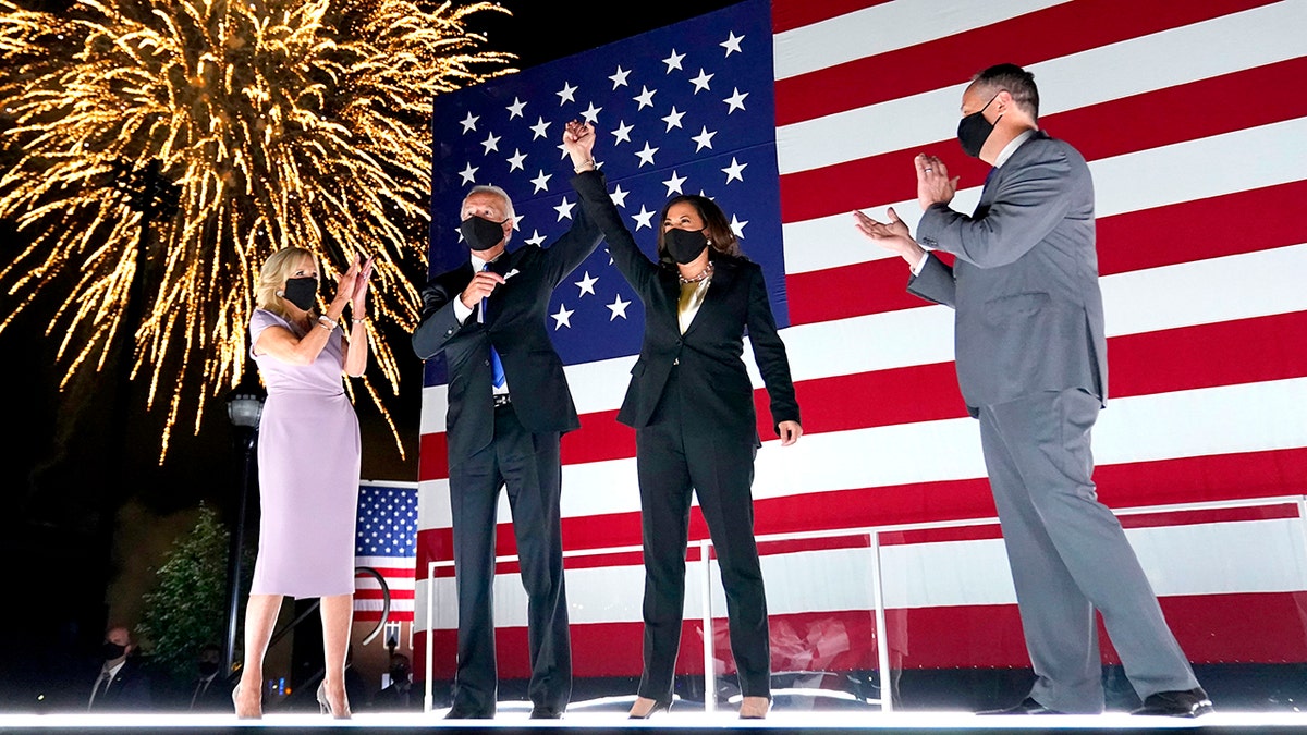 Democratic presidential candidate former Vice President Joe Biden, with Democratic vice presidential candidate Sen. Kamala Harris, D-Calif., raise their arms up as fireworks go off in the background during the fourth day of the Democratic National Convention, Thursday, Aug. 20, 2020, at the Chase Center in Wilmington, Del. Looking on are Jill Biden, far left, and Harris' husband Doug Emhoff, far right. (AP Photo/Andrew Harnik)