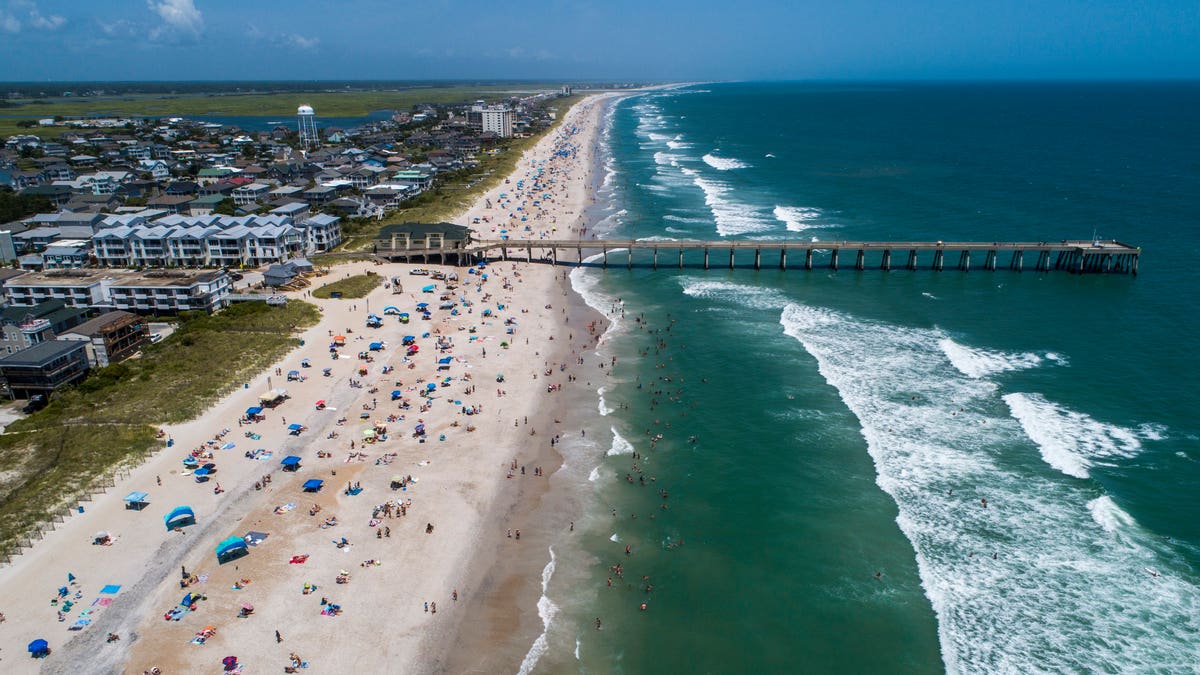 Beachgoers pack Wrightsville Beach, N.C., Sunday, Aug. 2, 2020 as Tropical Storm Isaias moves along the Southeast Coast. (Travis Long/The News &amp; Observer via AP)