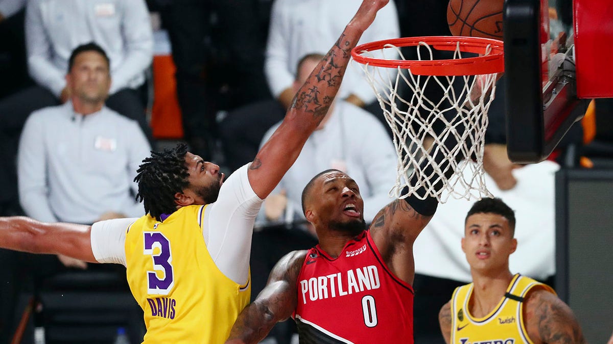 Los Angeles Lakers forward Anthony Davis (3) blocks a shot by Portland Trail Blazers guard Damian Lillard (0) as Lakers forward Kyle Kuzma (0) looks on during the first half of Game 2 of an NBA basketball first-round playoff series, Thursday, Aug. 20, 2020, in Lake Buena Vista, Fla. (Kim Klement/Pool Photo via AP)