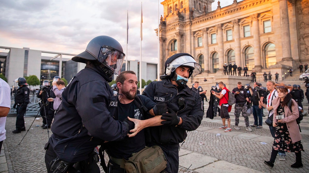 Police officers push away a crowd of demonstrators from the square 'Platz der Republik' in front of the Reichstag building during a demonstration against the Corona measures in Berlin, Germany, Saturday, Aug. 29, 2020. (Christoph Soeder/dpa via AP)