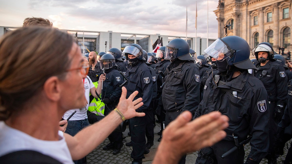 Police officers push away a crowd of demonstrators from the square 'Platz der Republik' in front of the Reichstag building during a demonstration against the Corona measures in Berlin, Germany, Saturday, Aug. 29, 2020. (Christoph Soeder/dpa via AP)