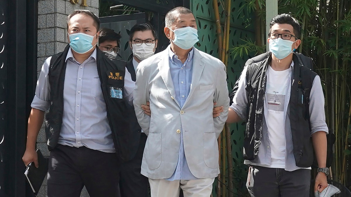 Hong Kong media tycoon Jimmy Lai, center, who founded local newspaper Apple Daily, is arrested by police officers at his home in Hong Kong, Monday, Aug. 10, 2020. (AP Photo)