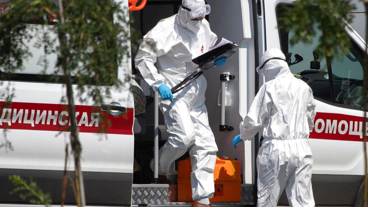 Medical workers wearing protective gear get out from an ambulance as they transport a patient suspected of having coronavirus, at a hospital in Kommunarka, outside Moscow, Russia, Tuesday, July 28, 2020. (AP Photo/Pavel Golovkin)