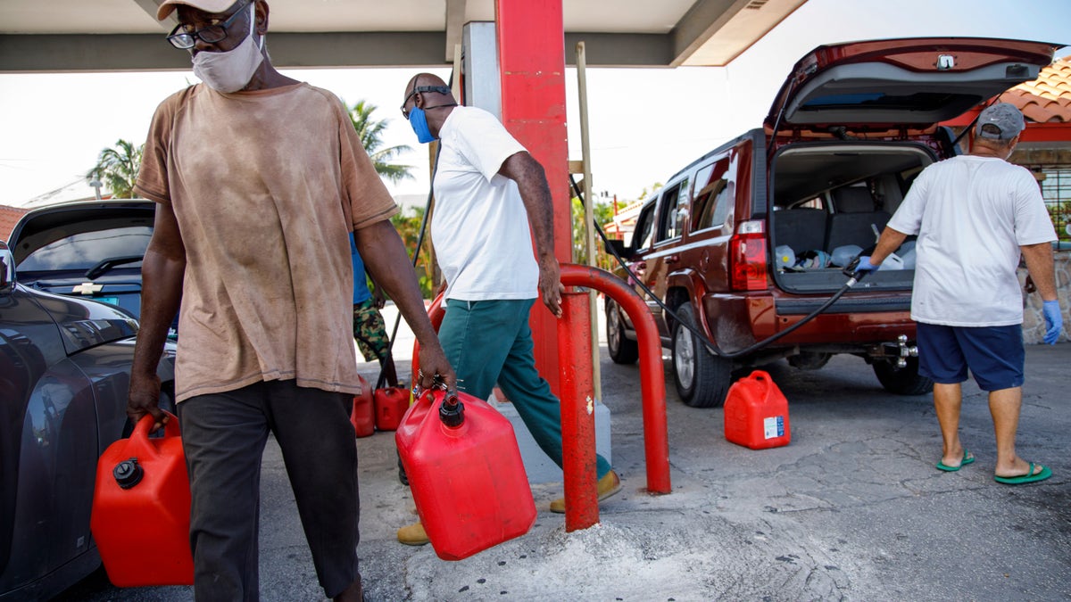 A resident walks with containers filled with gasoline at Cooper's gas station before the arrival of Hurricane Isaias in Freeport, Grand Bahama, Bahamas, Friday, July 31, 2020. (AP Photo/Tim Aylen)