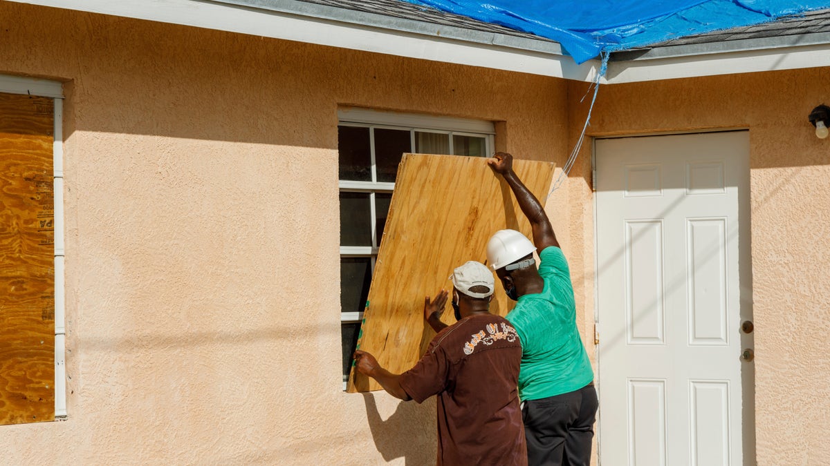 Residents cover a window with plywood in preparation for the arrival of Hurricane Isaias, in the Heritage neighborhood of Freeport, Grand Bahama, Bahamas, Friday, July 31, 2020. (AP Photo/Tim Aylen)