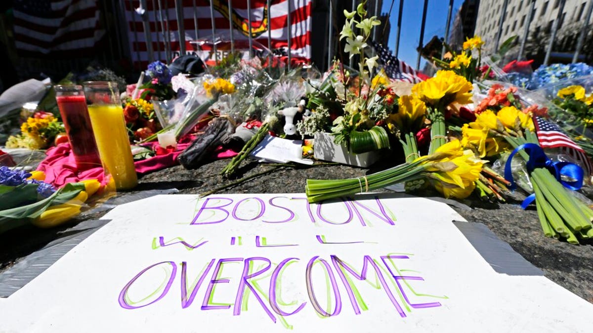FILE - In this April 17, 2013 photograph, flowers and signs adorn a barrier, two days after two explosions killed three and injured hundreds, at Boylston Street near the of finish line of the Boston Marathon at a makeshift memorial for victims and survivors of the bombing. A federal appeals court has overturned the death sentence of Dzhokhar Tsarnaev in the 2013 Boston Marathon bombing, Friday, July 31, 2020, saying the judge who oversaw the case didn't adequately screen jurors for potential biases. (AP Photo/Charles Krupa, File)