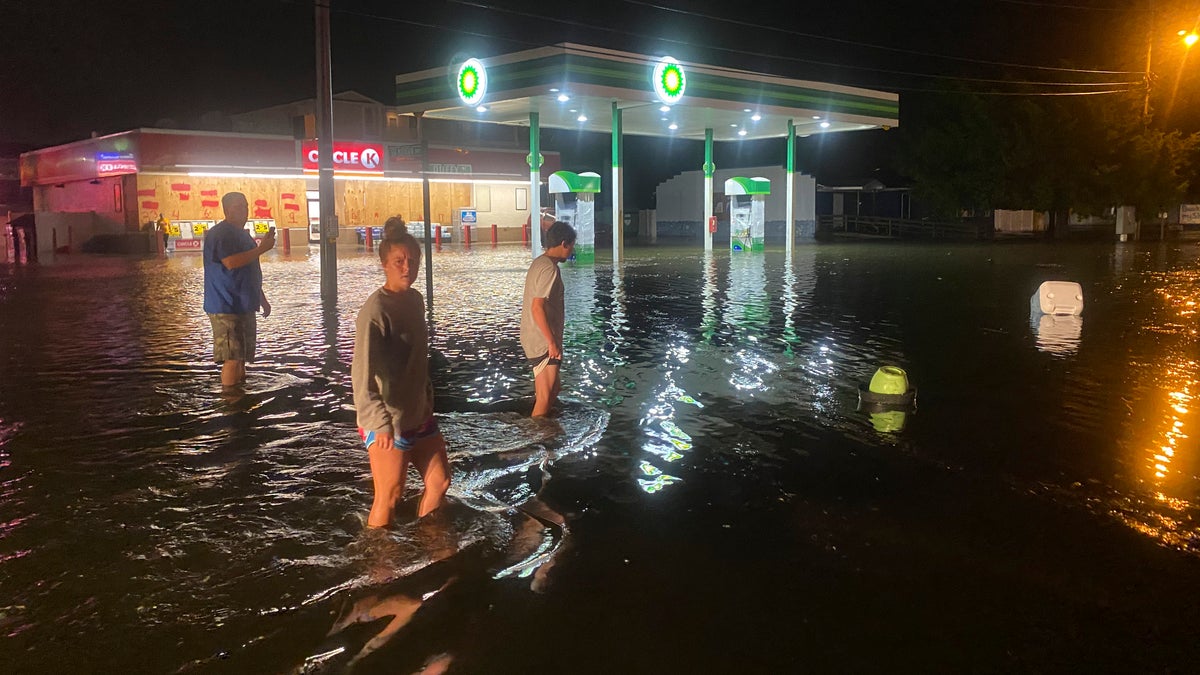 People walk on the flooded Sea Mountain Highway in North Myrtle Beach, S.C., as Isaias neared the Carolinas on Monday night, Aug. 3, 2020. (Jason Lee/The Sun News via AP)