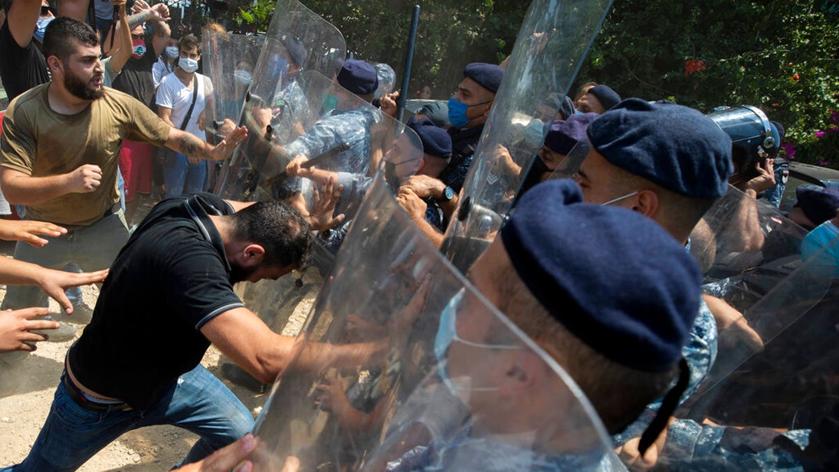 Riot police scuffle with anti-government protesters outside the Ministry of Energy and Water in Beirut, Lebanon, Tuesday, Aug. 4, 2020.  (AP Photo/Hassan Ammar)