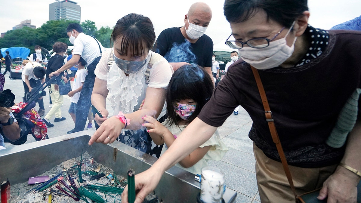 People burn joss sticks in front of the cenotaph for the atomic bombing victims before the start of a ceremony to mark the 75th anniversary of the U.S. bombing in Hiroshima, western Japan, early Thursday, Aug. 6, 2020. (AP Photo/Eugene Hoshiko)