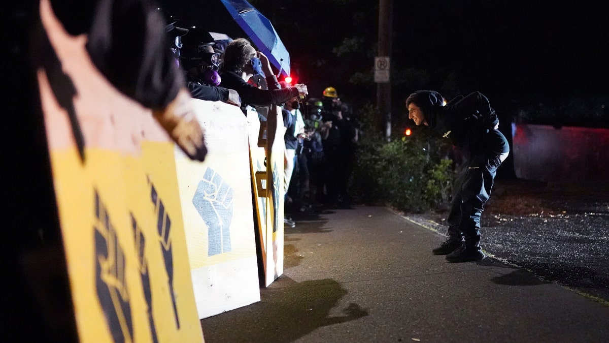 A protester taunts Portland police as they guard the Multnomah County Sheriff's Office on Friday, Aug. 7, 2020 in Portland, Ore. (AP Photo/Nathan Howard)