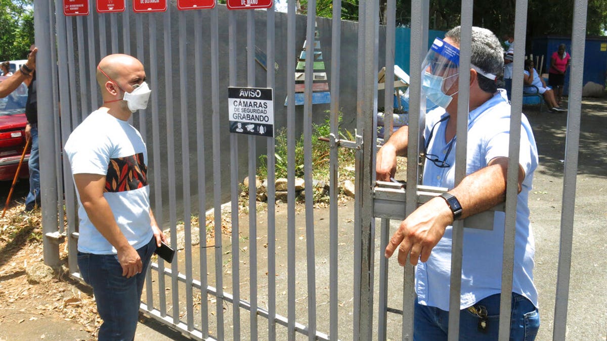 An electoral official, right, tells a voter that the ballots haven't arrived at a voting center in Carolina, Puerto Rico, Sunday, Aug. 9, 2020. Puerto Rico's primaries were marred on Sunday by a lack of ballots in a majority of centers across the U.S. territory, forcing frustrated voters who braved a spike in COVID-19 cases to turn around and go back home. 