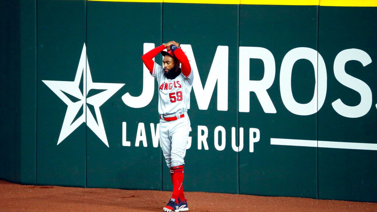 Los Angeles Angels right fielder Jo Adell puts his hands on his head after a fly ball by Texas Rangers' Nick Solak popped out of his glove and over the right field wall for a solo home run during the fifth inning of a baseball game in Arlington, Texas, Sunday, Aug. 9, 2020.