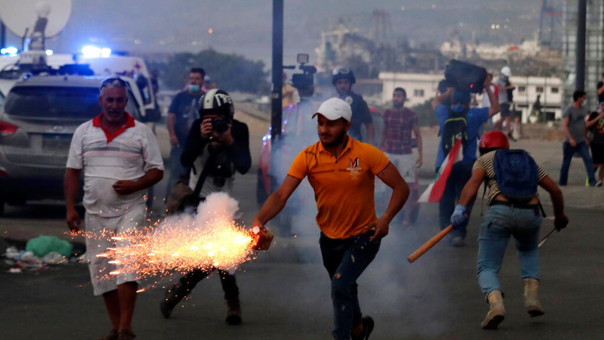 Anti-government protesters use fireworks against Lebanese riot police during a protest in the aftermath of last Tuesday's massive explosion. (AP Photo/Hassan Ammar)