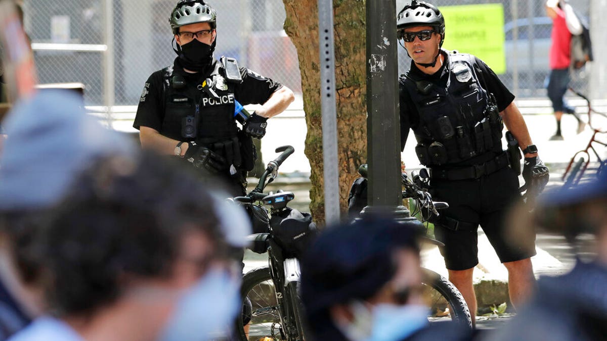 FILE: Police officers look on at protesters in Seattle.