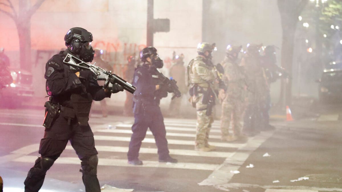 FILE - In this July 28, 2020, file photo, Federal officers deploy tear gas and crowd-control munitions at demonstrators during a protest at the federal courthouse in Portland, Ore. (AP Photo/Marcio Jose Sanchez, File)