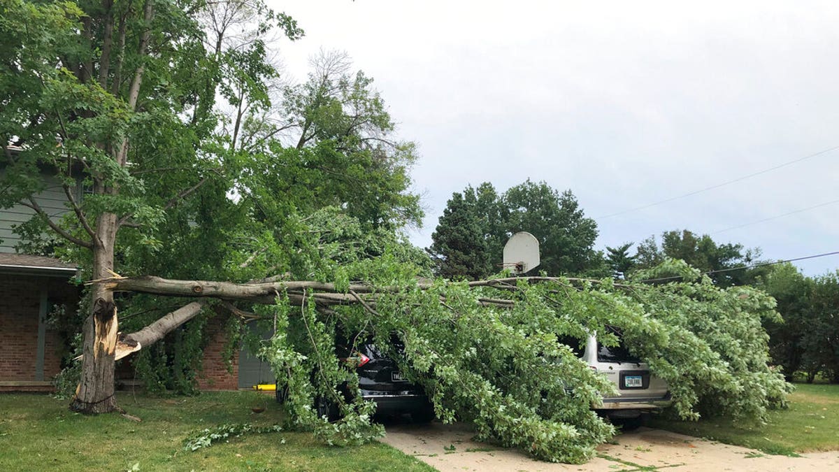 A tree fell across vehicles at a home in West Des Moines, Iowa, after a severe thunderstorm moved across Iowa on Monday, Aug. 10, 2020, downing trees, power lines and damaging buildings.