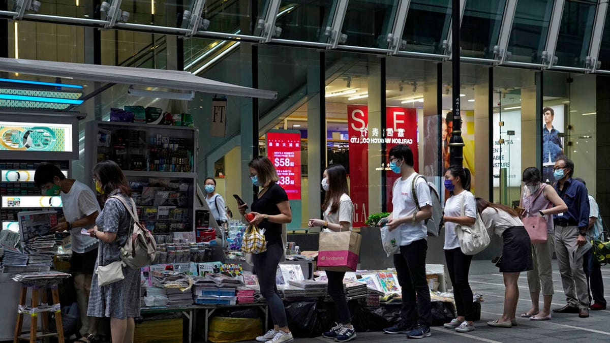 People queue up at a news stand to buy copies of Apple Daily at a downtown street in Hong Kong Tuesday, Aug. 11, 2020, as a show of support, a day after the arrest of its founder Jimmy Lai. 