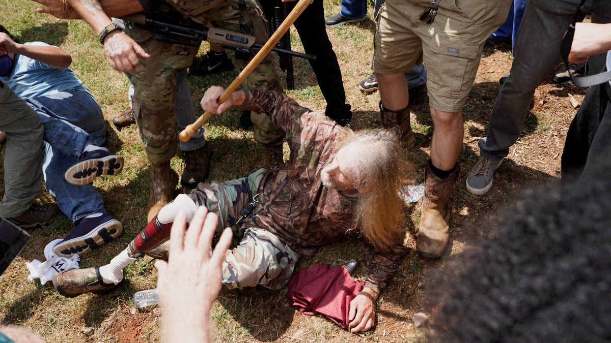 A man falls after being hit by counter demonstrators during a protest Aug. 15, in Stone Mountain Village, Ga. (AP Photo/John Bazemore)