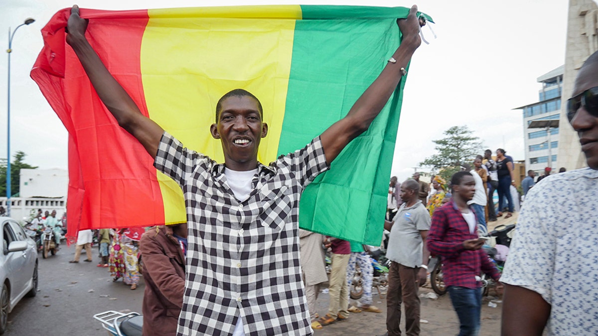 A man holds a national flag as he celebrates with others in the streets in the capital Bamako, Mali Tuesday, Aug. 18, 2020. Mutinous soldiers detained Mali's president and prime minister Tuesday after surrounding a residence and firing into the air in an apparent coup attempt after several months of demonstrations calling for President Ibrahim Boubacar Keita's ouster. (AP Photo)