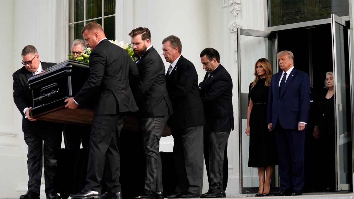 President Donald Trump and first lady Melania Trump hold hands as they watch people carry the casket of Robert Trump out of the White House after a memorial service for the president's younger brother on Friday, Aug 21, 2020, in Washington. (AP Photo/Evan Vucci)