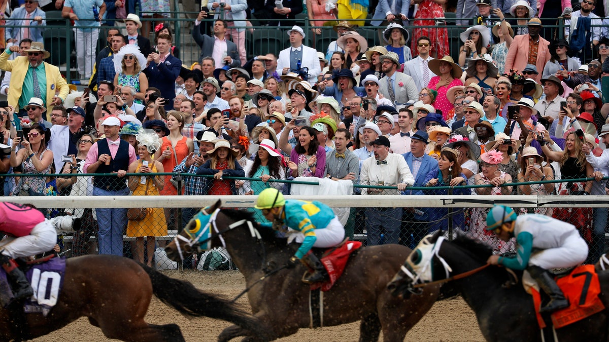 FILE - In this May 4, 2019, file photo, fans cheer as they watch a race at Churchill Downs before the 145th running of the Kentucky Derby horse race in Louisville, Ky. (AP Photo/John Minchillo, File)