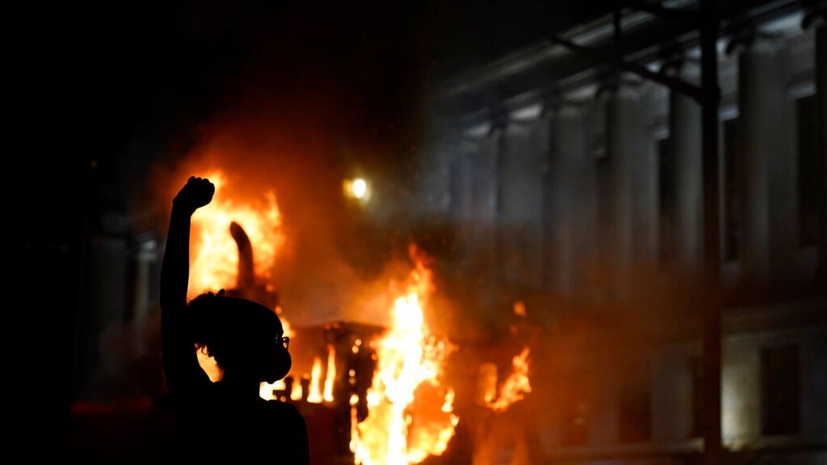 A protester stands in a cloud of tear gas near a burning garbage truck outside the Kenosha County Courthouse Monday. (AP Photo/David Goldman)