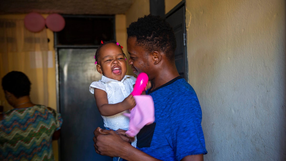 A man holds up his 1-year-old daughter at his house in Port-au-Prince, Haiti, Tuesday, Aug. 25, 2020. (Associated Press)