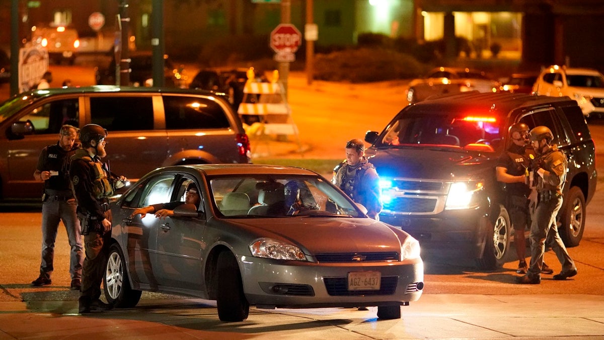 Police stop a car near where protesters gather for a fourth night to demonstrate against the police shooting of Jacob Blake in Kenosha, Wis., late Wednesday. (AP Photo/David Goldman)