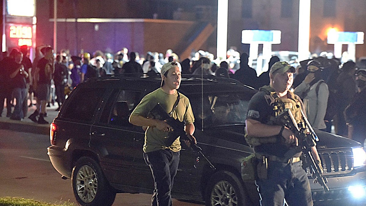 Kyle Rittenhouse, left, with backwards cap, walks along Sheridan Road in Kenosha, Wis., on Tuesday with another armed civilian. (Adam Rogan/The Journal Times via AP)