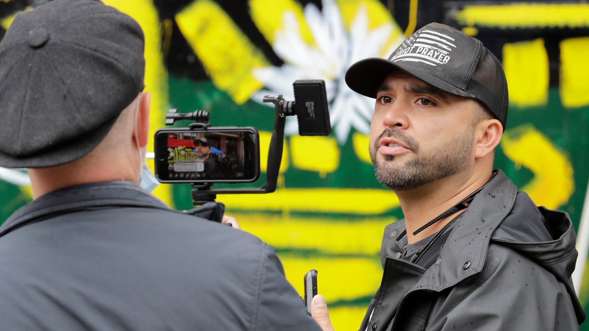 In this June 15, 2020, file photo, Joey Gibson, right, founder of the right-wing group Patriot Prayer, takes part in a livestream video broadcast, inside what has been named the Capitol Hill Occupied Protest zone in Seattle. (AP Photo/Ted S. Warren, File)