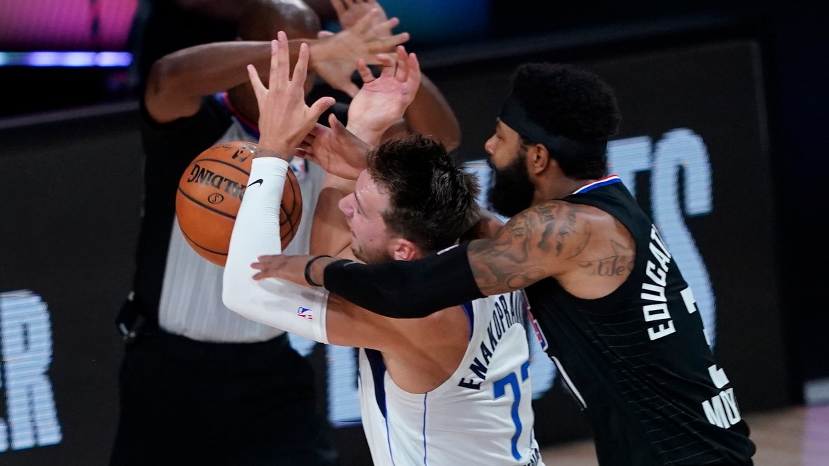 Dallas Mavericks' Luka Doncic (77) is fouled by Los Angeles Clippers' Marcus Morris Sr. during the first half of an NBA first round playoff game Sunday, Aug. 30, 2020, in Lake Buena Vista, Fla. (AP Photo/Ashley Landis)