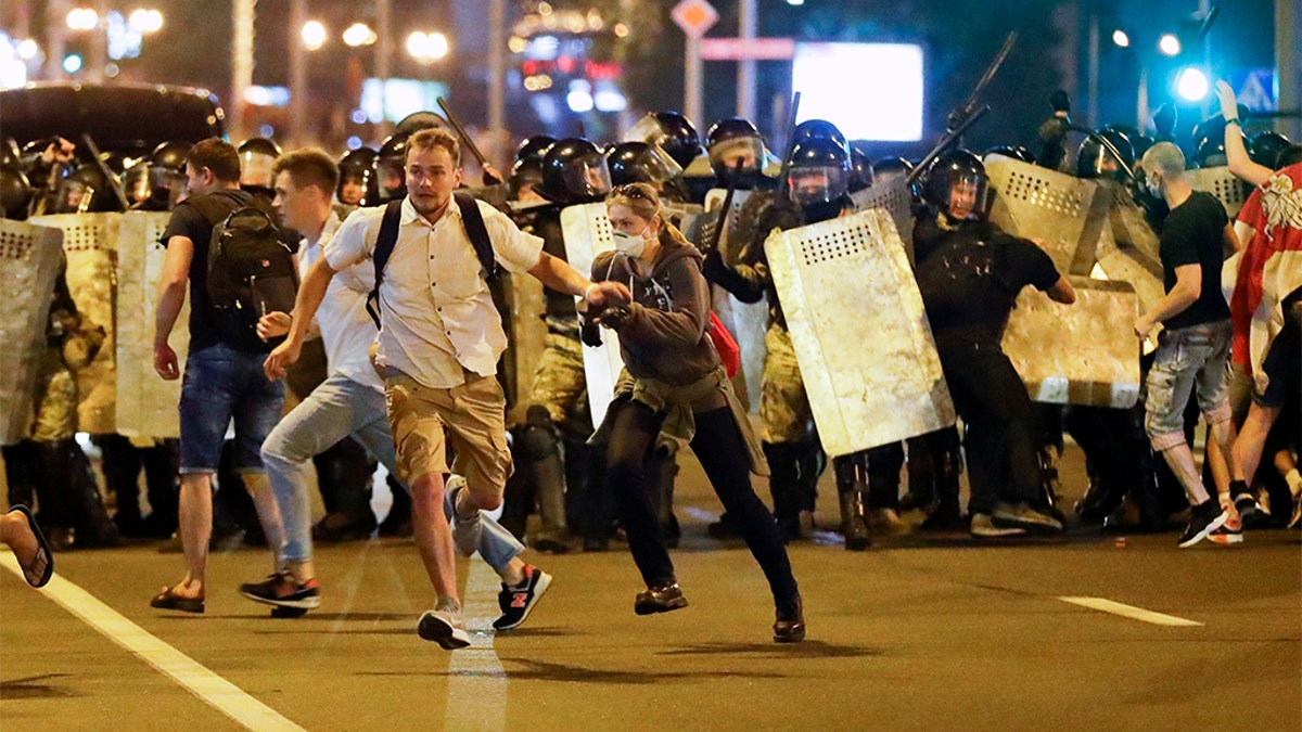 Demonstrators run away from police as they gather to protest against a result of the Belarusian presidential election in Minsk, Belarus, Sunday, Aug. 9, 2020. Police and protesters clashed in Belarus' capital and the major city of Brest on Sunday after the presidential election in which the authoritarian leader who has ruled for a quarter-century sought a sixth term in office.