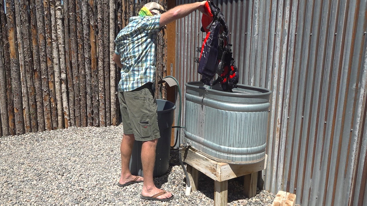 Matthew Gontram, owner of New Mexico River Adventures, demonstrates the business' new cleaning procedures, which include dunking life jackets into a cleaning solution and setting them aside for 48 hours.