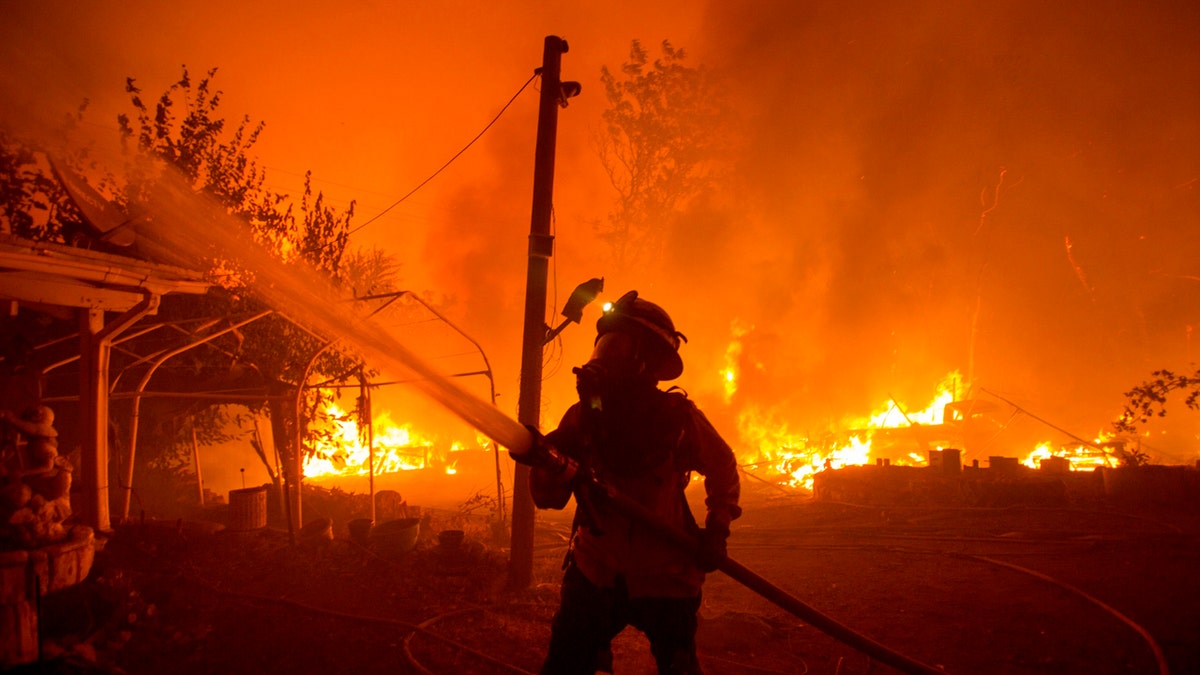 In this Aug. 12, 2020, file photo, a firefighter works against the Lake Hughes Fire in Angeles National Forest north of Santa Clarita, Calif.