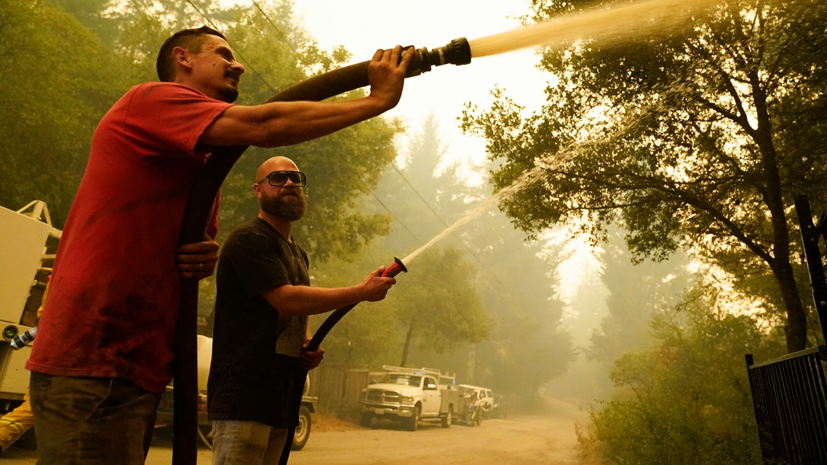 In this Aug. 20, 2020, file photo, civilian volunteers Brian Alvarez, left, and Nate Bramwell fight the CZU Lightning Complex Fire in Bonny Doon, Calif.