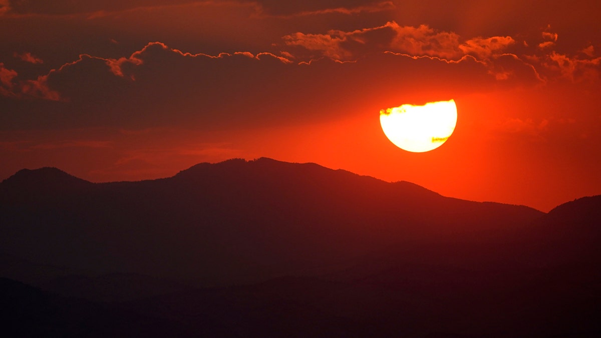The sun sets behind the Rocky Mountains and turns the sky red as wildfires burn across the state Monday, Aug. 17, 2020, in this view from Denver.