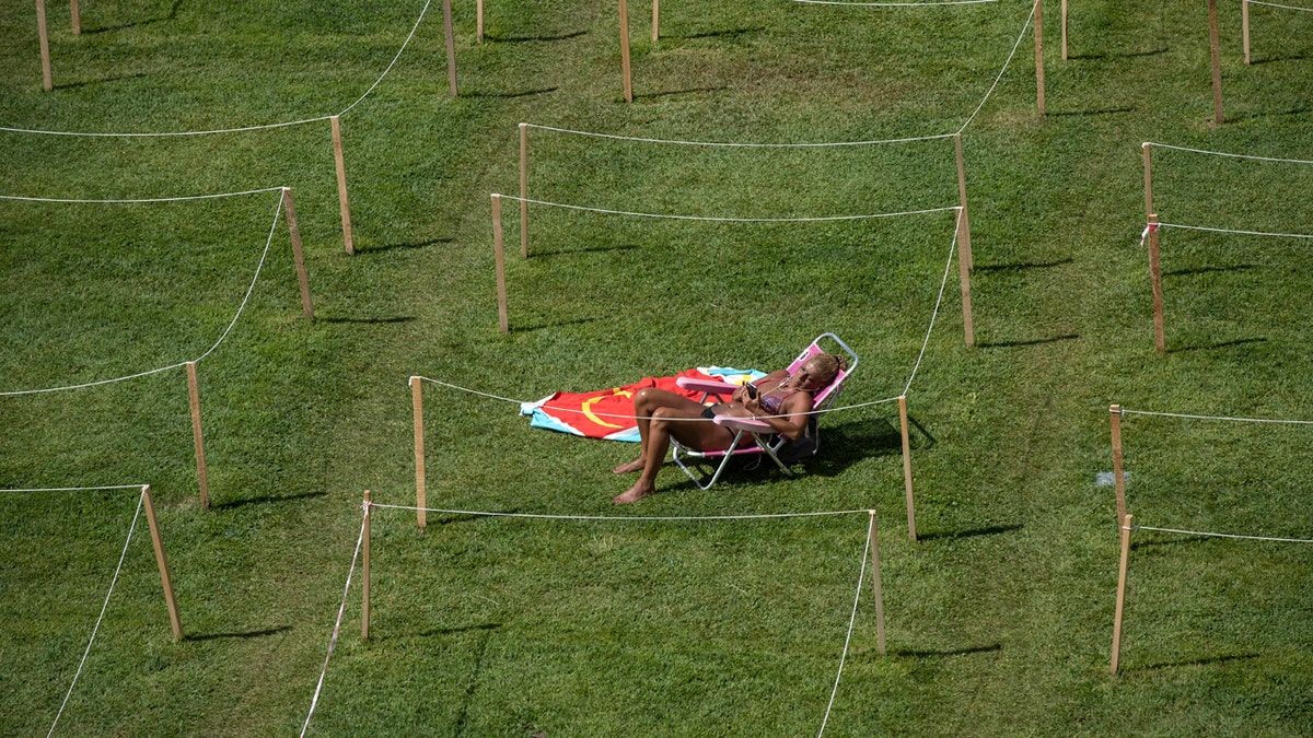 A sunbather checks her smartphone on a hot day of summer in Rivas Vaciamadrid, Spain, Wednesday, July 29, 2020.