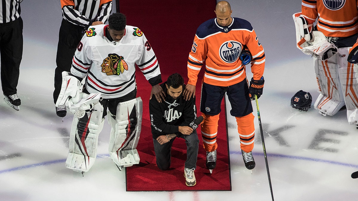 The Minnesota Wild's Matt Dumba takes a knee during the national anthem flanked by the Edmonton Oilers' Darnell Nurse, right, and the Chicago Blackhawks' Malcolm Subban before an NHL hockey Stanley Cup playoff game in Edmonton, Alberta, Saturday, Aug. 1, 2020. (Jason Franson/The Canadian Press via AP)