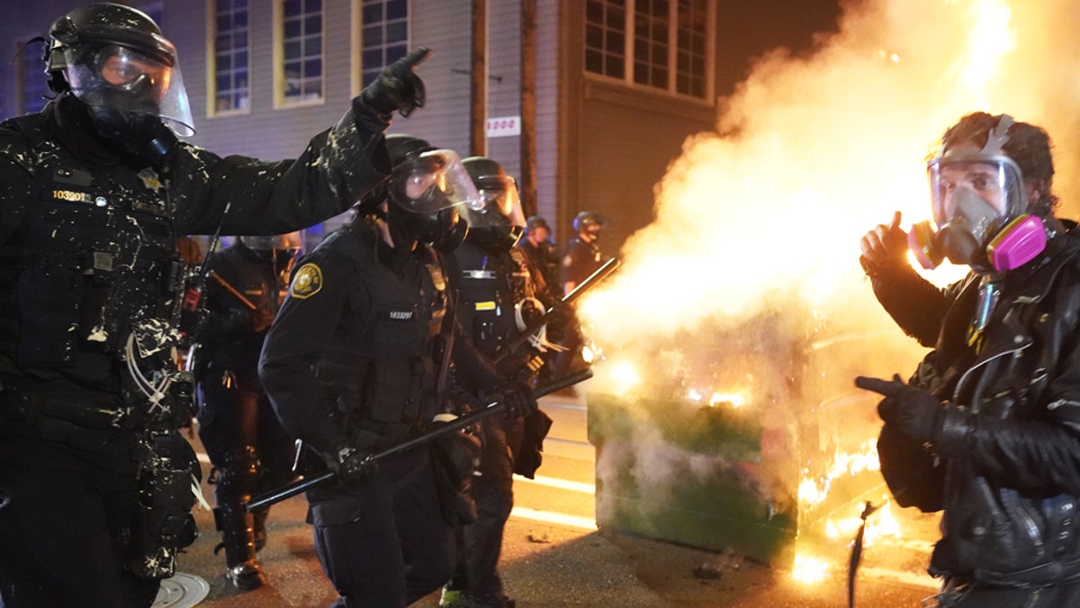 Portland police officers push protesters past a dumpster fire during a dispersal from in front of the Immigration and Customs Enforcement (ICE) detention facility in the early morning on Aug. 21, 2020, in Portland, Ore. (Nathan Howard/Getty Images)