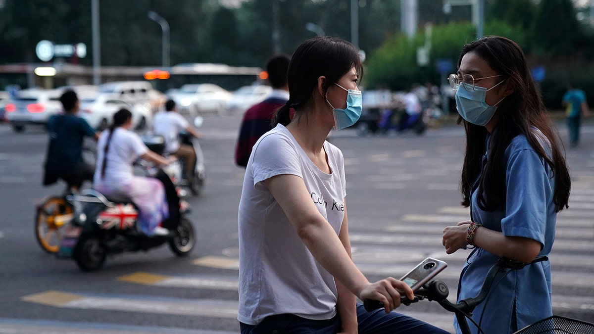 Women wearing face masks following the coronavirus disease (COVID-19) outbreak chat on a street in Beijing, China August 11, 2020. (REUTERS/Tingshu Wang)