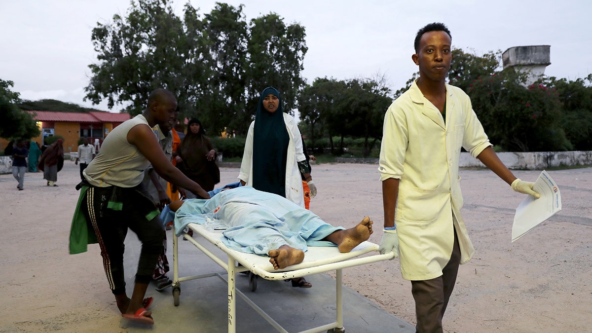 Paramedics and civilians carry an injured person on a stretcher at Madina hospital after a blast at the Elite Hotel in Lido beach in Mogadishu, Somalia August 16, 2020. (Reuters/Feisal Omar)