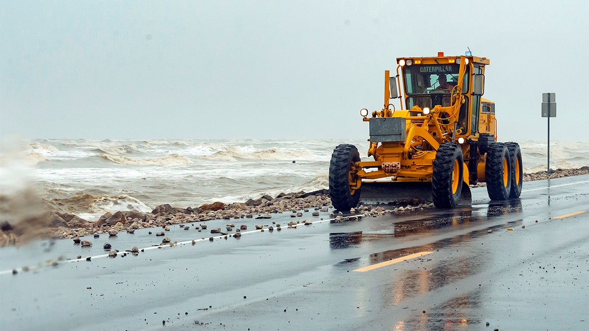 State highway workers use earth movers to get the rocks, shells, sand and other debris off Texas State Highway 87, on the Bolivar Peninsula, Texas, along the beach on Saturday morning, July 25. Even though Hurricane Hanna made landfall several hundred miles south of the Bolivar Peninsula, the storm still had an effect on the area. (Fran Ruchalski/The Beaumont Enterprise via AP)