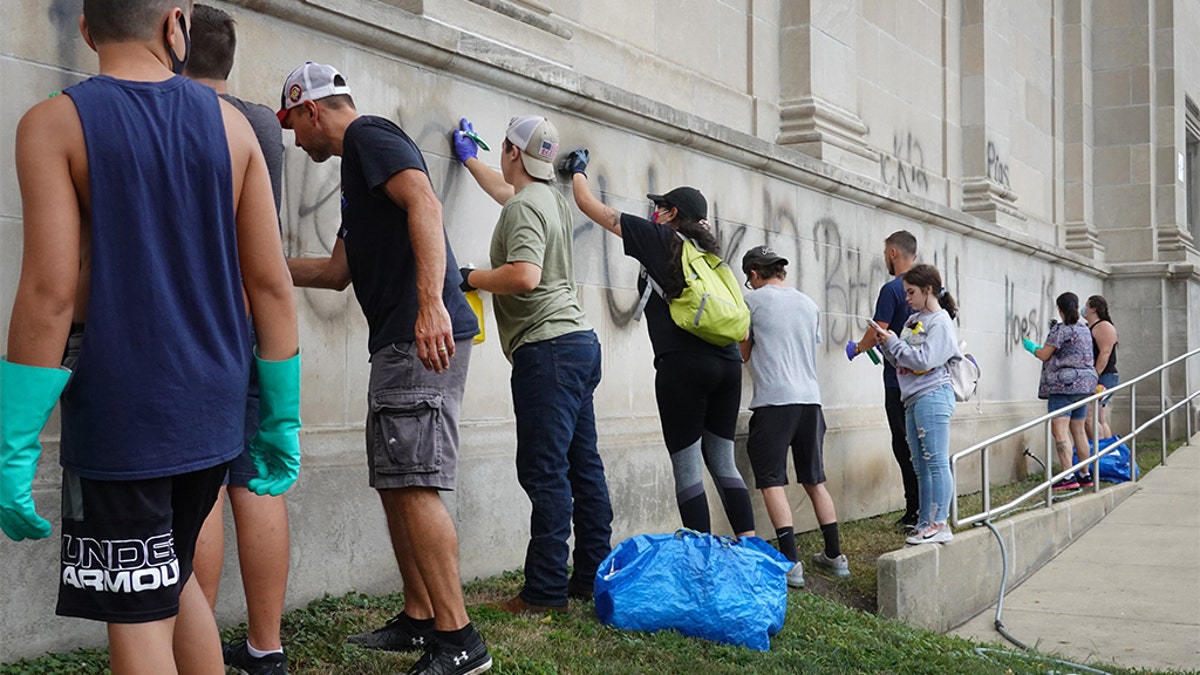 Volunteers clean graffiti from a high school near the Kenosha County Courthouse following another night of unrest on Aug. 25 in Kenosha, Wis.  (Photo by Scott Olson/Getty Images)