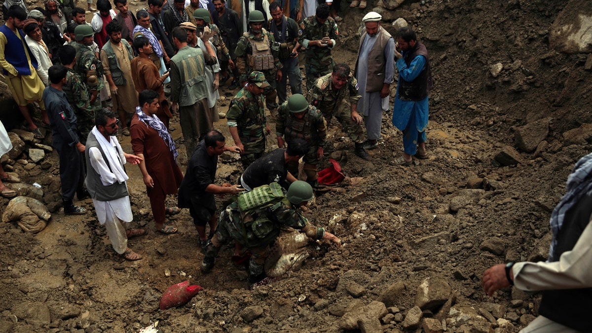 Soldiers and civilians search for bodies after a mudslide caused by heavy flooding, in Parwan province, north of Kabul, Afghanistan, Wednesday, Aug. 26, 2020.